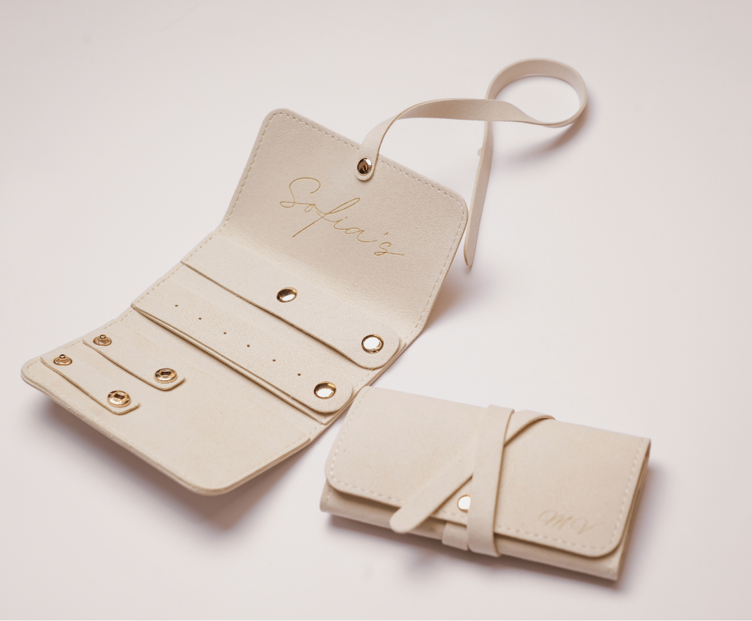 Beige leather jewellery organizer with strap on a light pink background