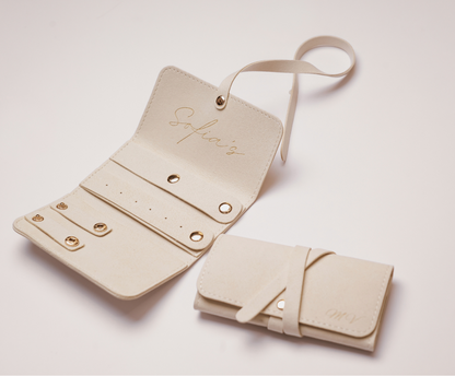 Beige leather jewellery organizer with strap on a light pink background